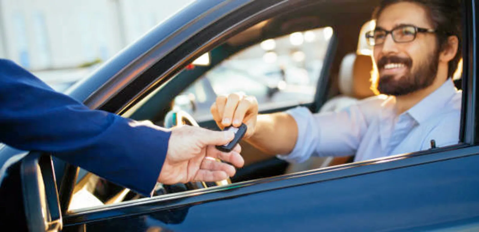 a person sitting in car and handing over a car key